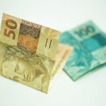 Person reviewing bank savings statements and euro coins