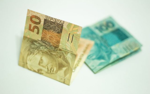 Person reviewing bank savings statements and euro coins
