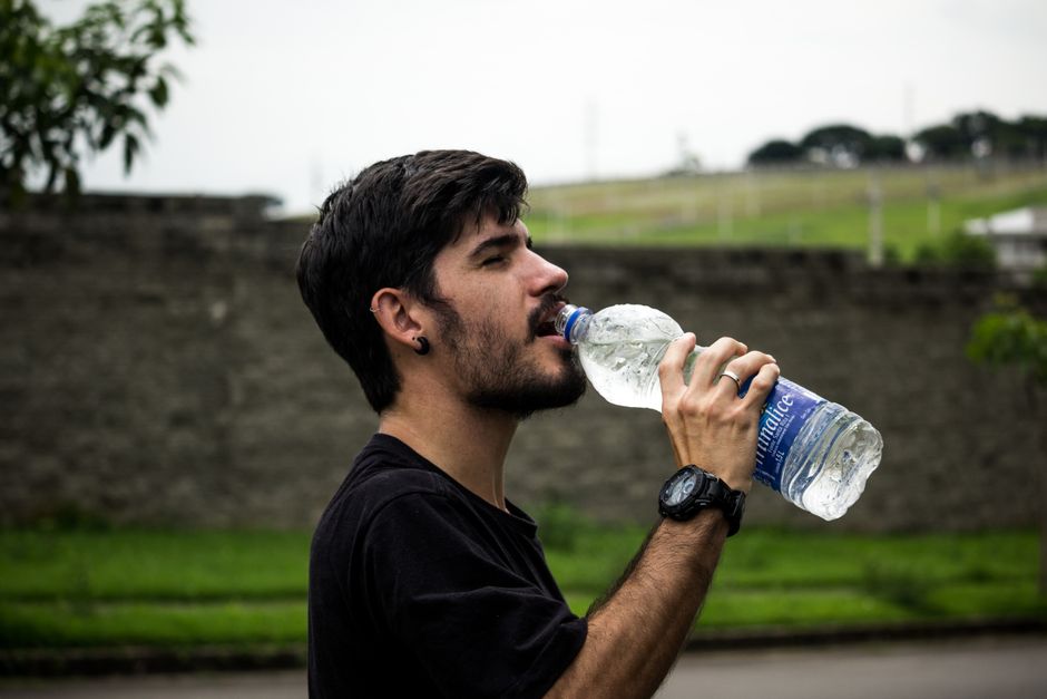 Person drinking water outdoors during a hot summer day