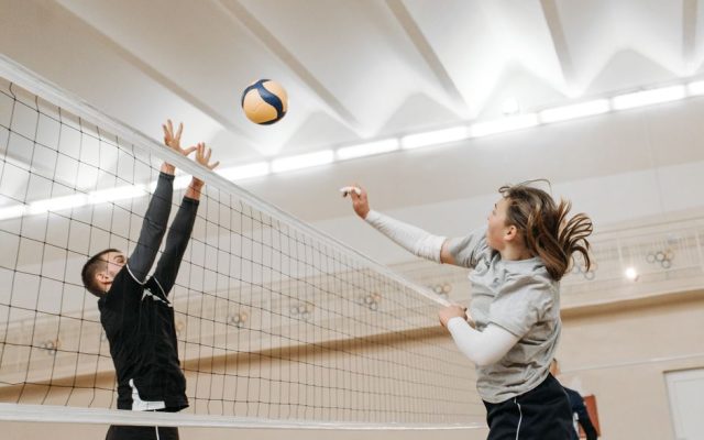 Volleyball players competing in a sports hall during a tournament