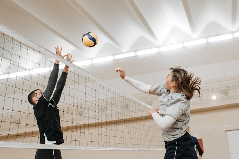 Volleyball players competing in a sports hall during a tournament